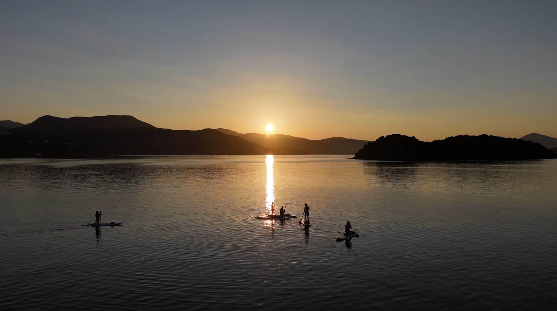 白沙洲日落航拍全景，直立板隊伍在金黃色海面上划行